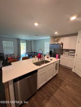 a large white kitchen with sink a microwave and cabinets