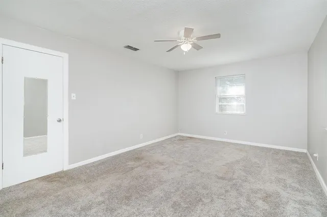 an empty room with windows and fan