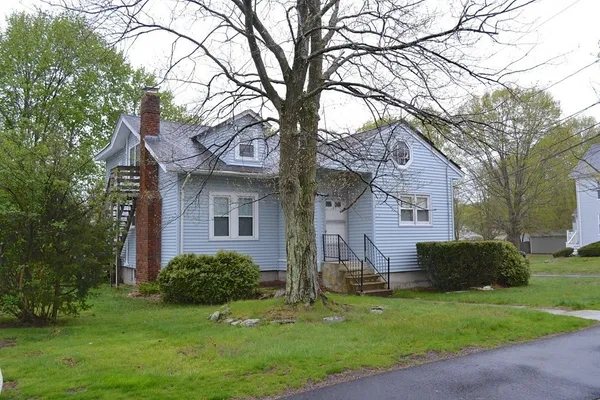 a front view of a house with a yard and a tree