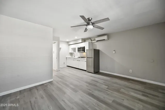 a view of a livingroom with wooden floor a ceiling fan and windows