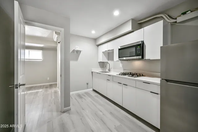 a kitchen with granite countertop a refrigerator a sink a stove and microwave