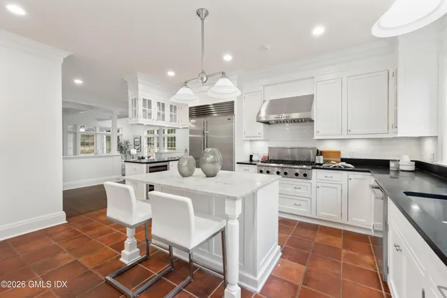 a kitchen with stainless steel appliances granite countertop a sink a stove a refrigerator and white cabinets with wooden floor