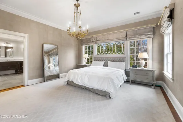 a spacious bedroom with a large bed and a chandelier