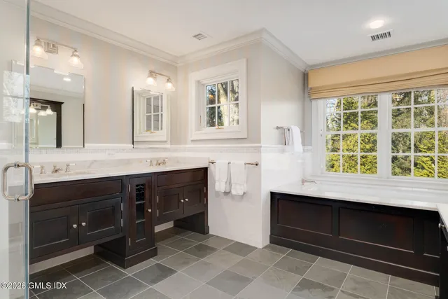 a spacious bathroom with a granite countertop double vanity sink a mirror and a bathtub