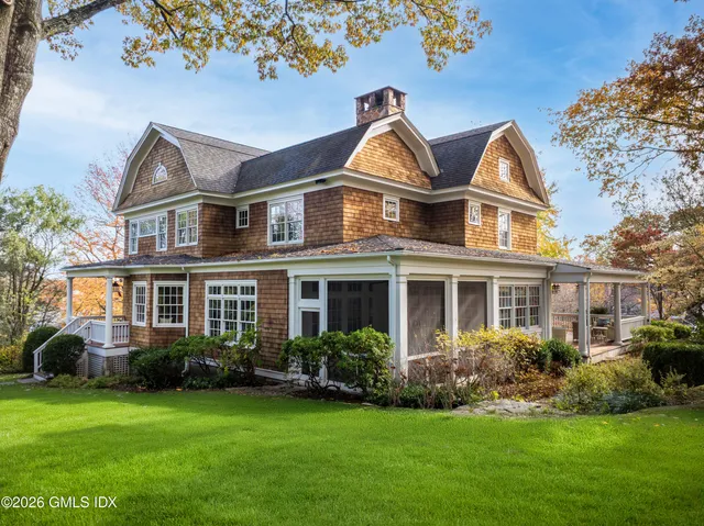 a view of a big yard in front of a brick house with large windows