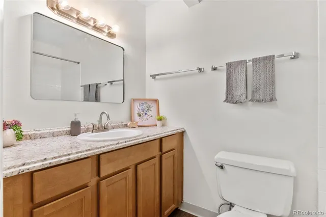 a bathroom with a granite countertop sink a toilet and mirror