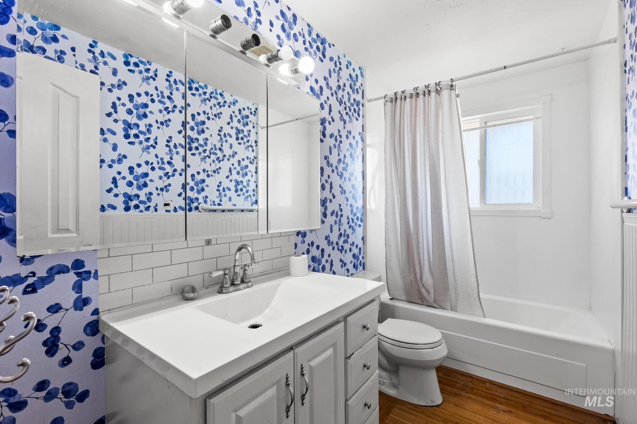 6295 West Grandview Place Boise, ID 83709 - Photo 16 of 29 Full bath featuring shower / bath combo with shower curtain, dark wood-style floors, vanity, and decorative backsplash