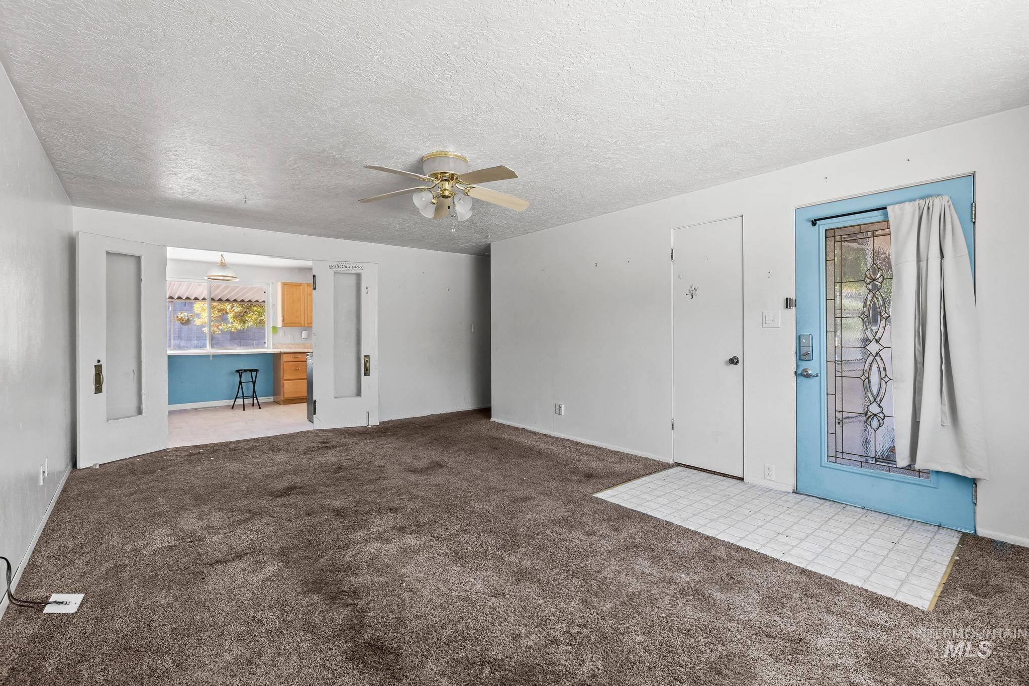 6295 West Grandview Place Boise, ID 83709 - Photo 9 of 29 Unfurnished living room featuring a textured ceiling, carpet, and ceiling fan