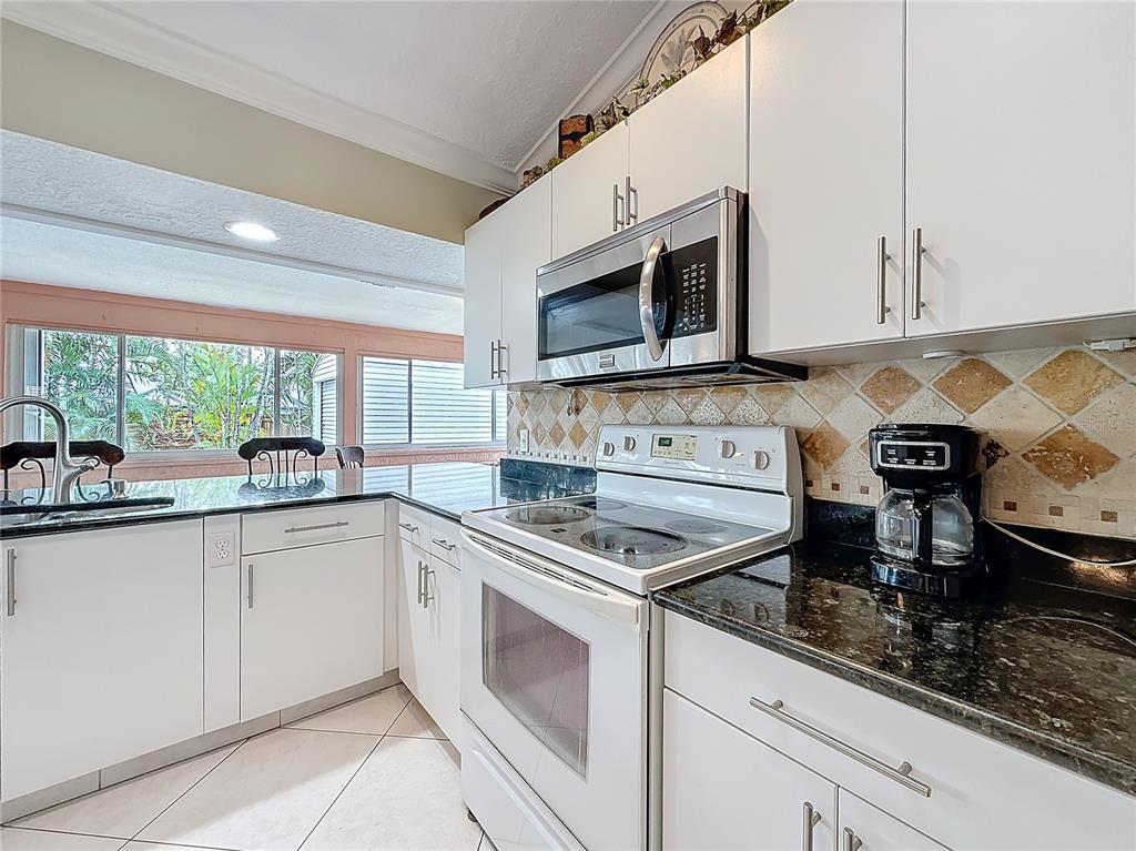 2686 Southwest Fairgreen Road Port St. Lucie, FL 34987 - Photo 12 of 36 a kitchen with stainless steel appliances granite countertop a sink stove and microwave