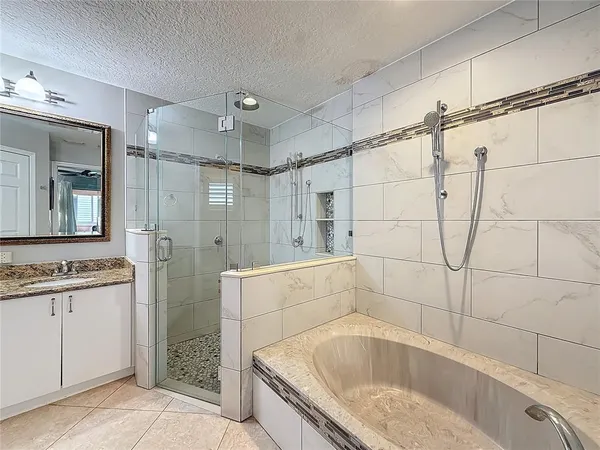 a bathroom with a granite countertop bathtub shower sink and mirror