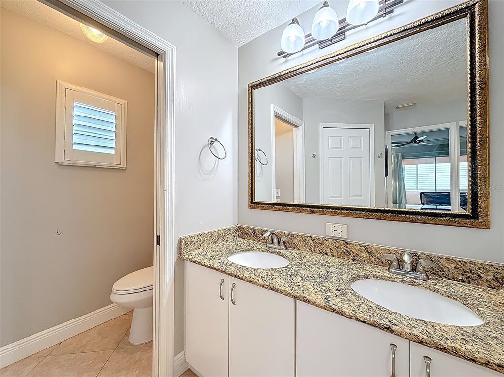 2686 Southwest Fairgreen Road Port St. Lucie, FL 34987 - Photo 17 of 36 a bathroom with a granite countertop sink a toilet and a mirror