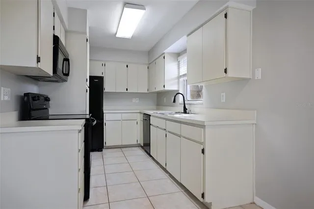 a kitchen with a sink dishwasher a stove and white cabinets