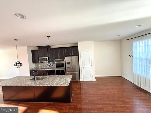 a view of kitchen with refrigerator stove and wooden floor
