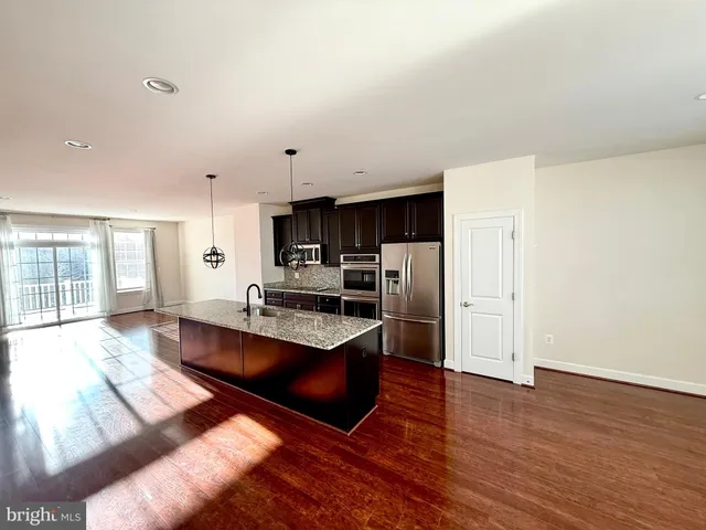 a large kitchen with granite countertop a large counter top stainless steel appliances and cabinets