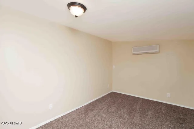 an empty room with chandelier fan and windows