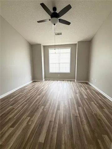 a view of empty room with wooden floor and fan