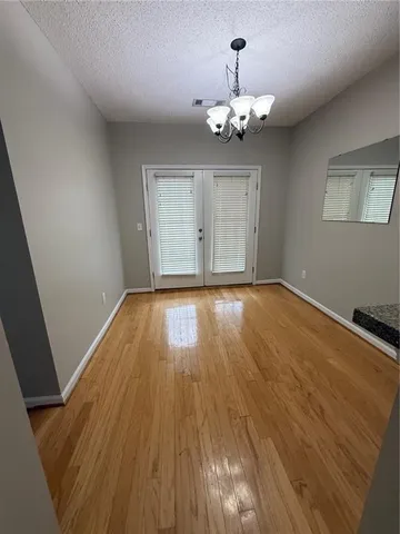 a view of an empty room with wooden floor and chandelier