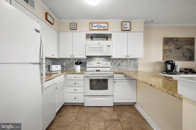 a kitchen with granite countertop white cabinets and white appliances