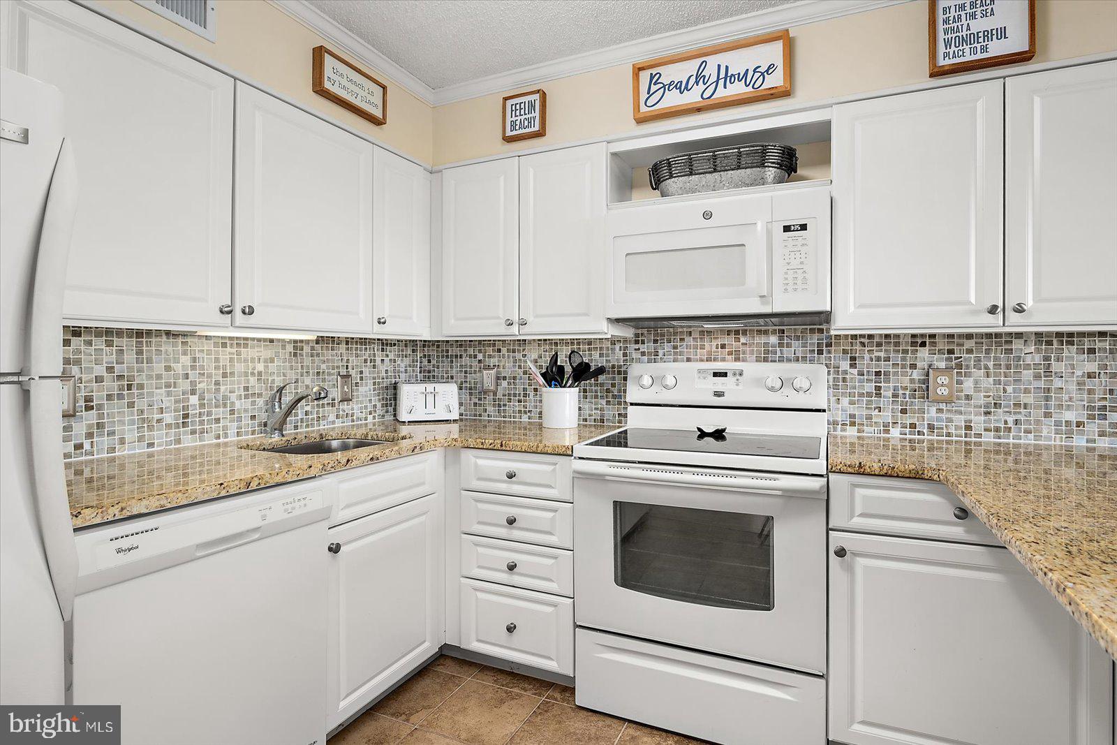 119 Old Landing Road, Unit 102A Ocean City, MD 21842 - Photo 19 of 47 a kitchen with granite countertop white cabinets and white appliances