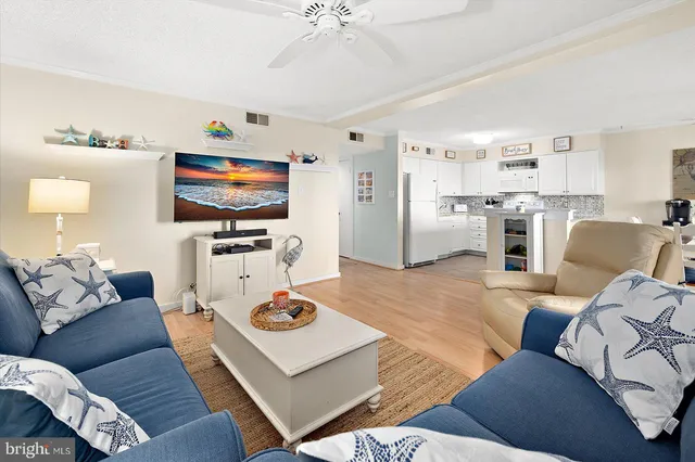 a kitchen with stainless steel appliances kitchen island granite countertop a refrigerator a stove a sink and white cabinets with wooden floor