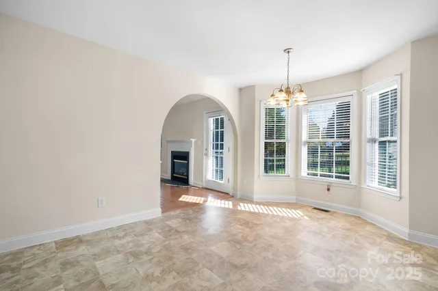 a view of an empty room with chandelier fan and windows