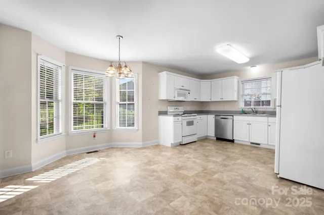 a kitchen with stainless steel appliances granite countertop a stove a sink dishwasher a refrigerator and white cabinets with wooden floor