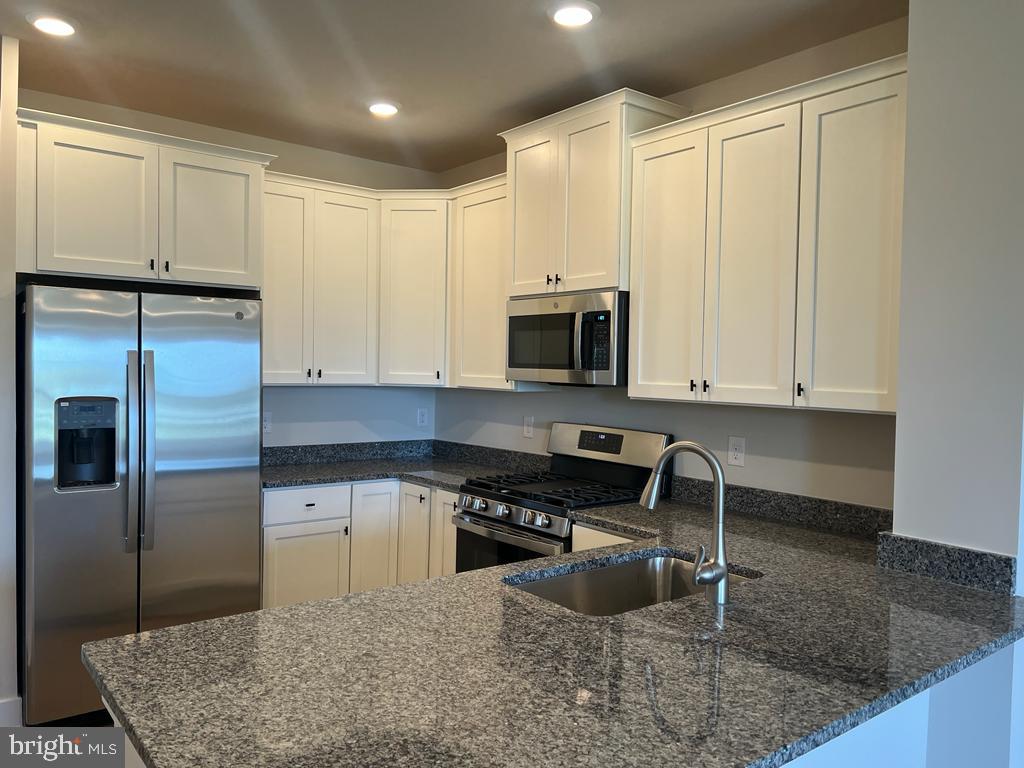 a kitchen with stainless steel appliances granite countertop a sink a stove and a microwave