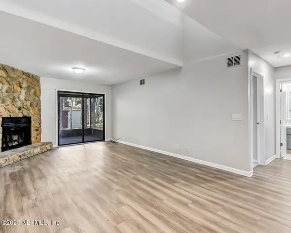 a view of an empty room with window and fireplace