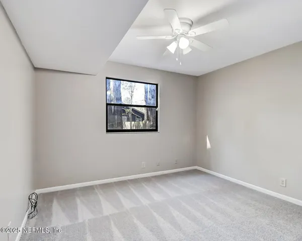 an empty room with windows and fan