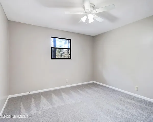 an empty room with a window and a fan