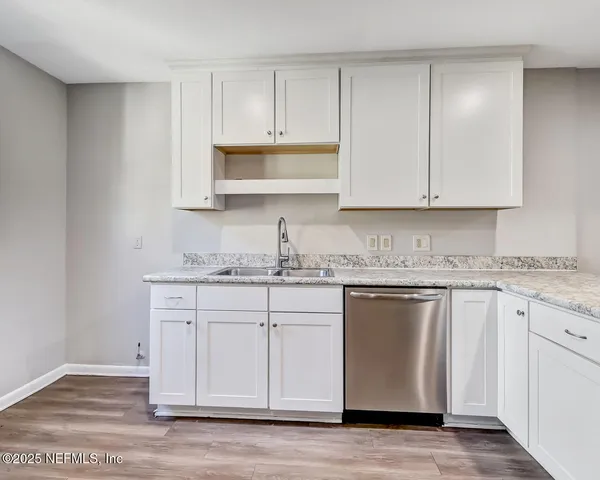 a kitchen with granite countertop white cabinets and a sink