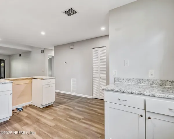 a large white kitchen with a sink and dishwasher with wooden floor