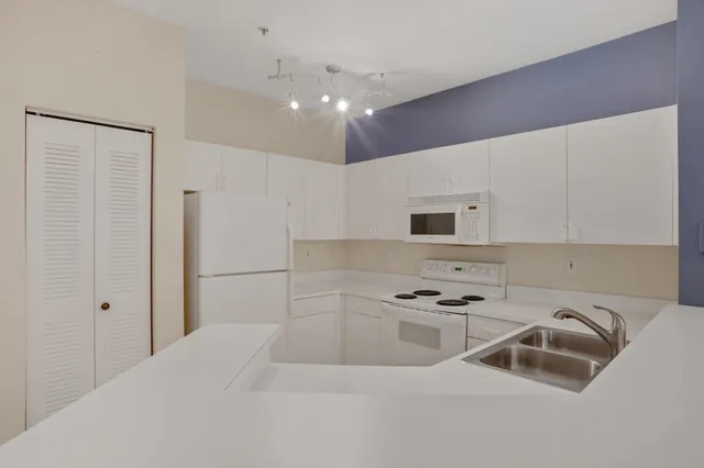 a kitchen with granite countertop a sink cabinets and stainless steel appliances
