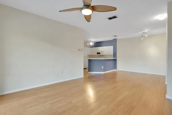 an empty room with chandelier fan and windows