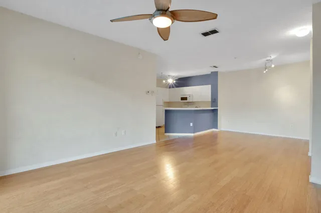 an empty room with chandelier fan and windows