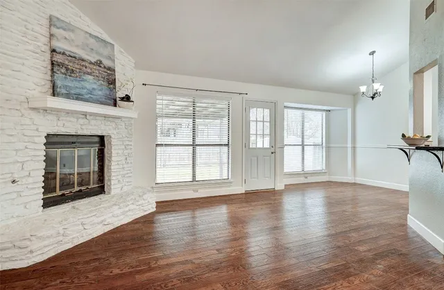 wooden floor fireplace and windows in an empty room