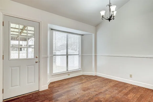 an empty room with wooden floor cabinet and windows