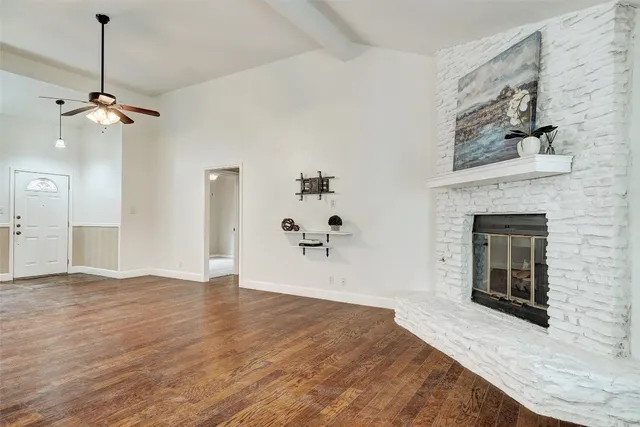 a view of an empty room with a fireplace and wooden floor