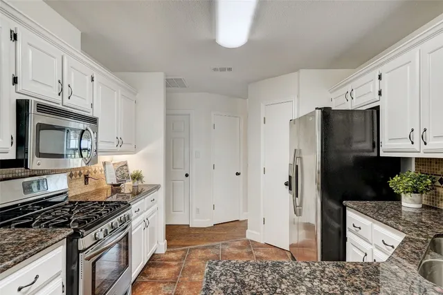 a kitchen with stainless steel appliances granite countertop a refrigerator and a stove