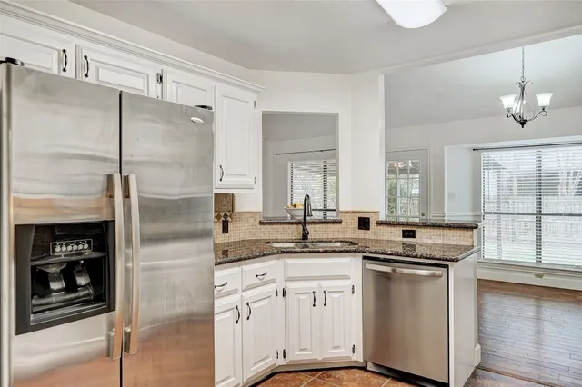 a kitchen with stainless steel appliances granite countertop a sink and a refrigerator