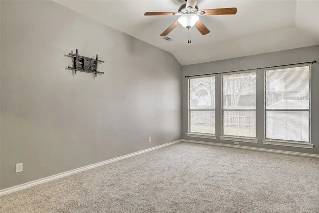 an empty room with windows and chandelier fan