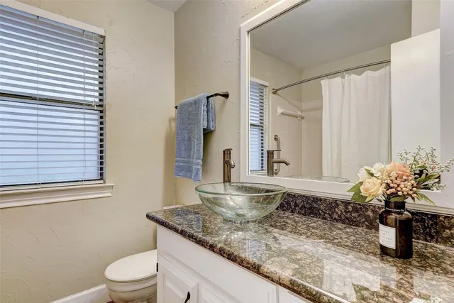a bathroom with a granite countertop sink a toilet and mirror