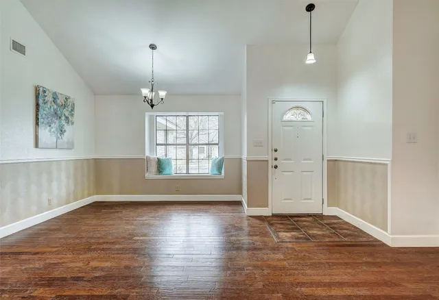 an empty room with wooden floor cabinet and windows
