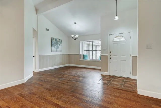 an empty room with wooden floor cabinet and windows