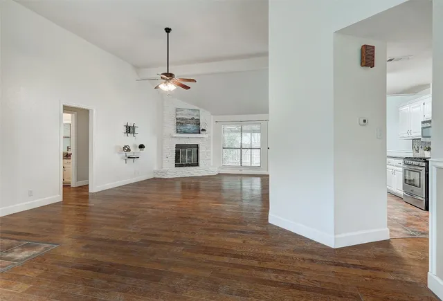 a view of empty room with wooden floor and ceiling fan