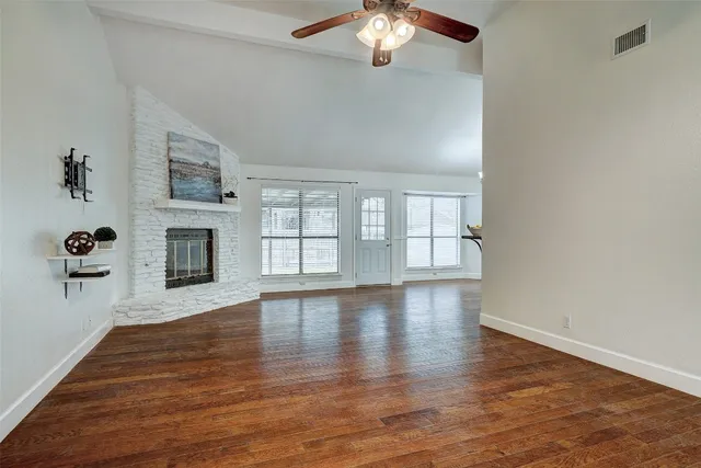 a view of an empty room with wooden floor and a fireplace