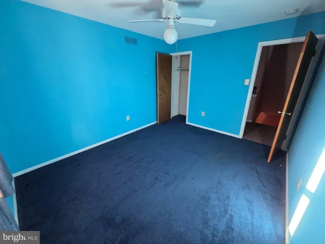 an empty room with a chandelier fan and a window