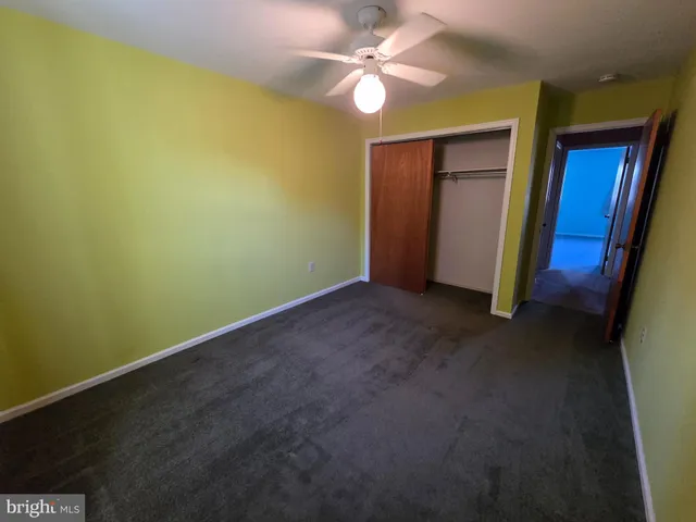 a view of an empty room with closet and a chandelier fan