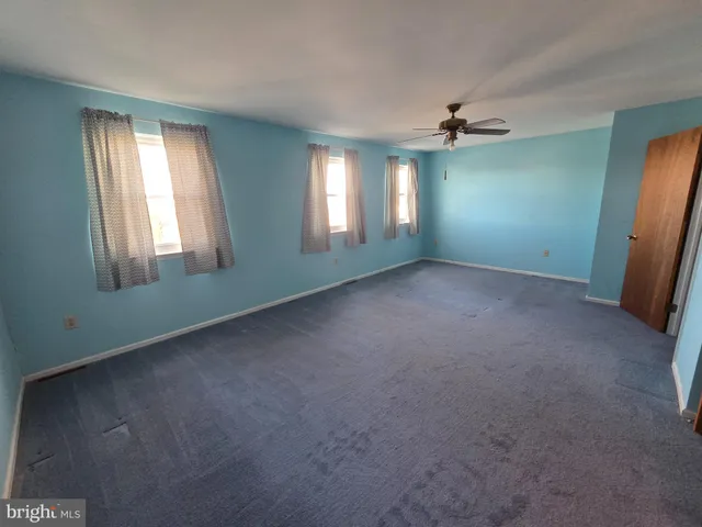 an empty room with a window and a ceiling fan