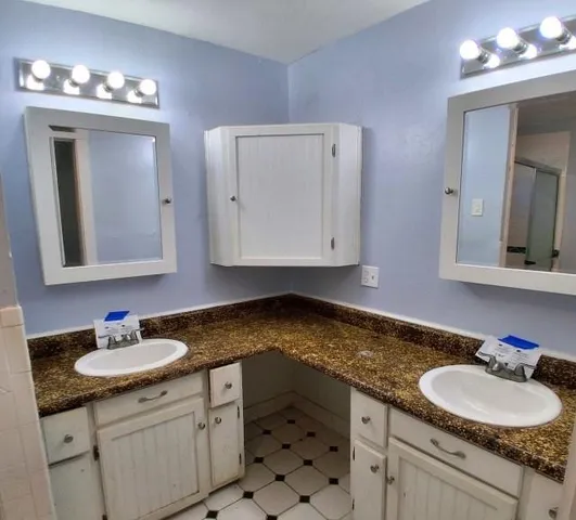 a bathroom with a granite countertop sink double and mirror